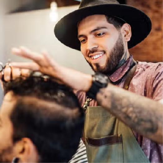 A barber cutting a mans hair in a high street barber shop