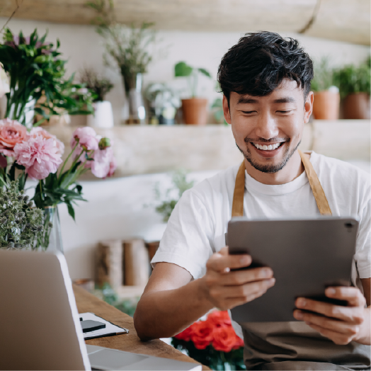 A man smiling at his laptop in a high street florist shop